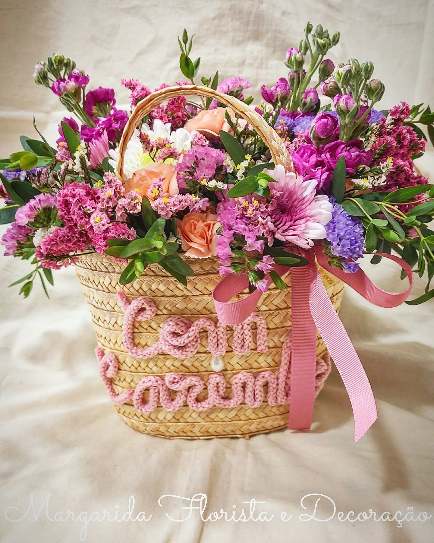 Cesto de palha com flores variadas e fita rosa