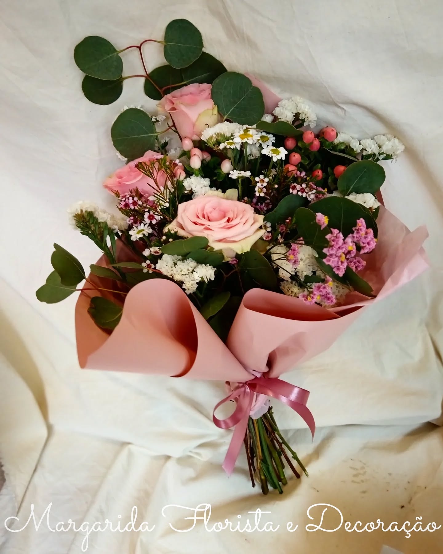 Bouquet de flores rosa e brancas com folhas verdes, embrulhado em papel rosa