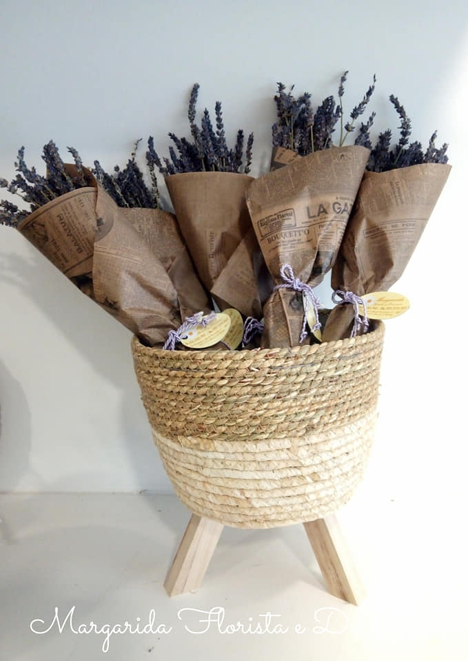 Vasos com flores secas de lavanda em papel castanho dentro de cesto de palha com base de madeira