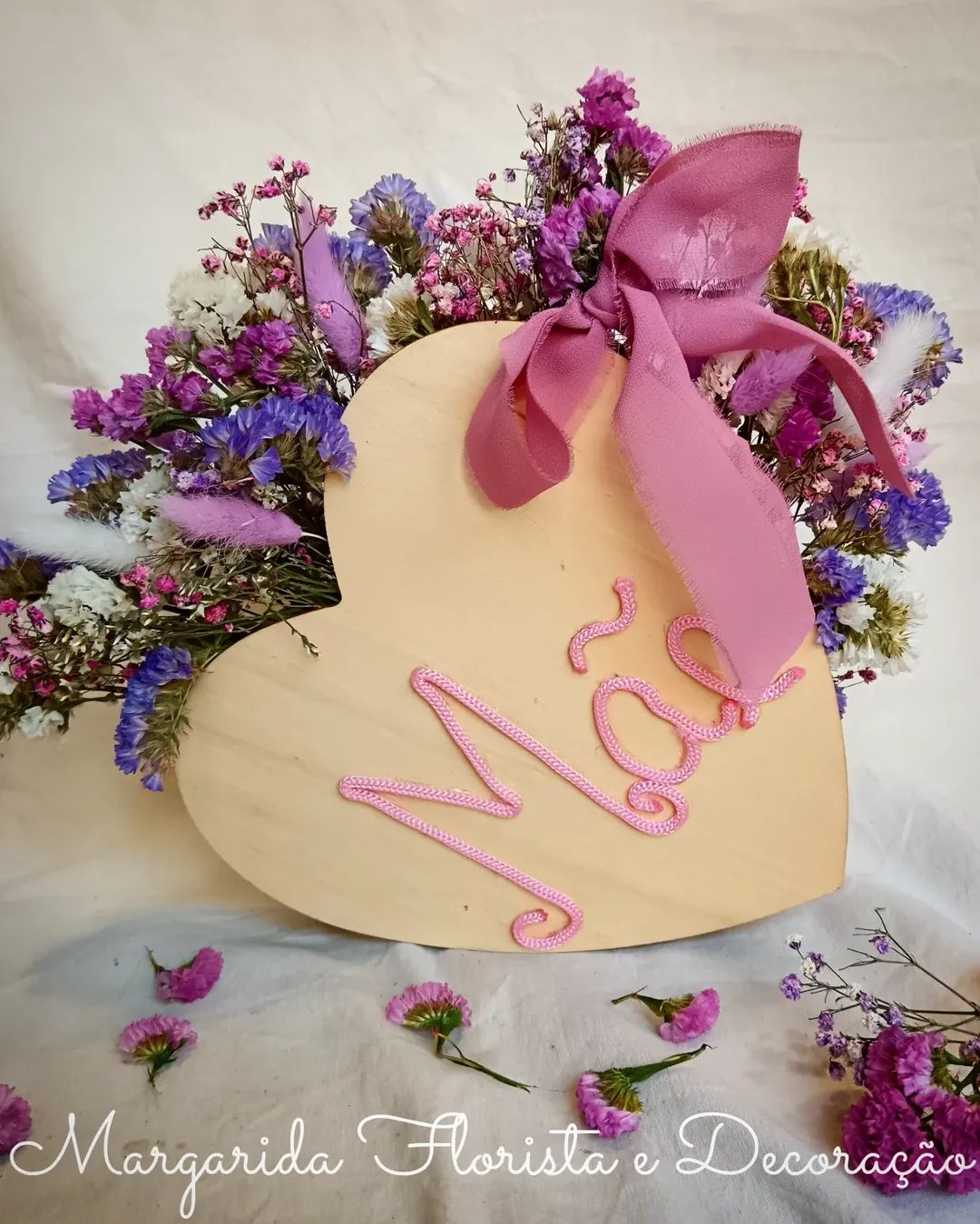 Arranjo floral seco em forma de coração com decoração em cordão rosa e fita rosa