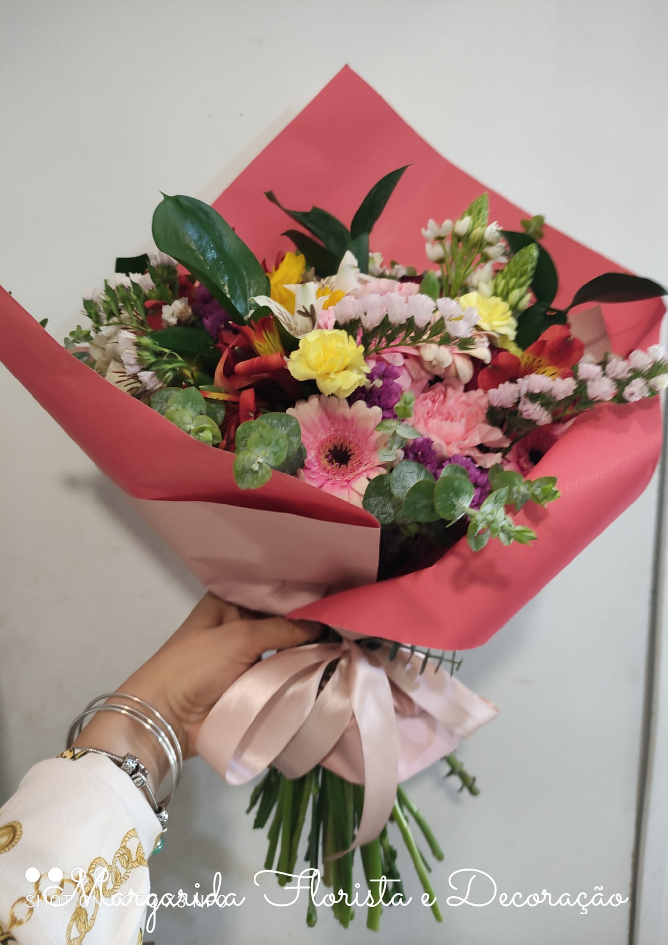 Ramo de flores coloridas embrulhado em papel rosa com fita cor-de-rosa