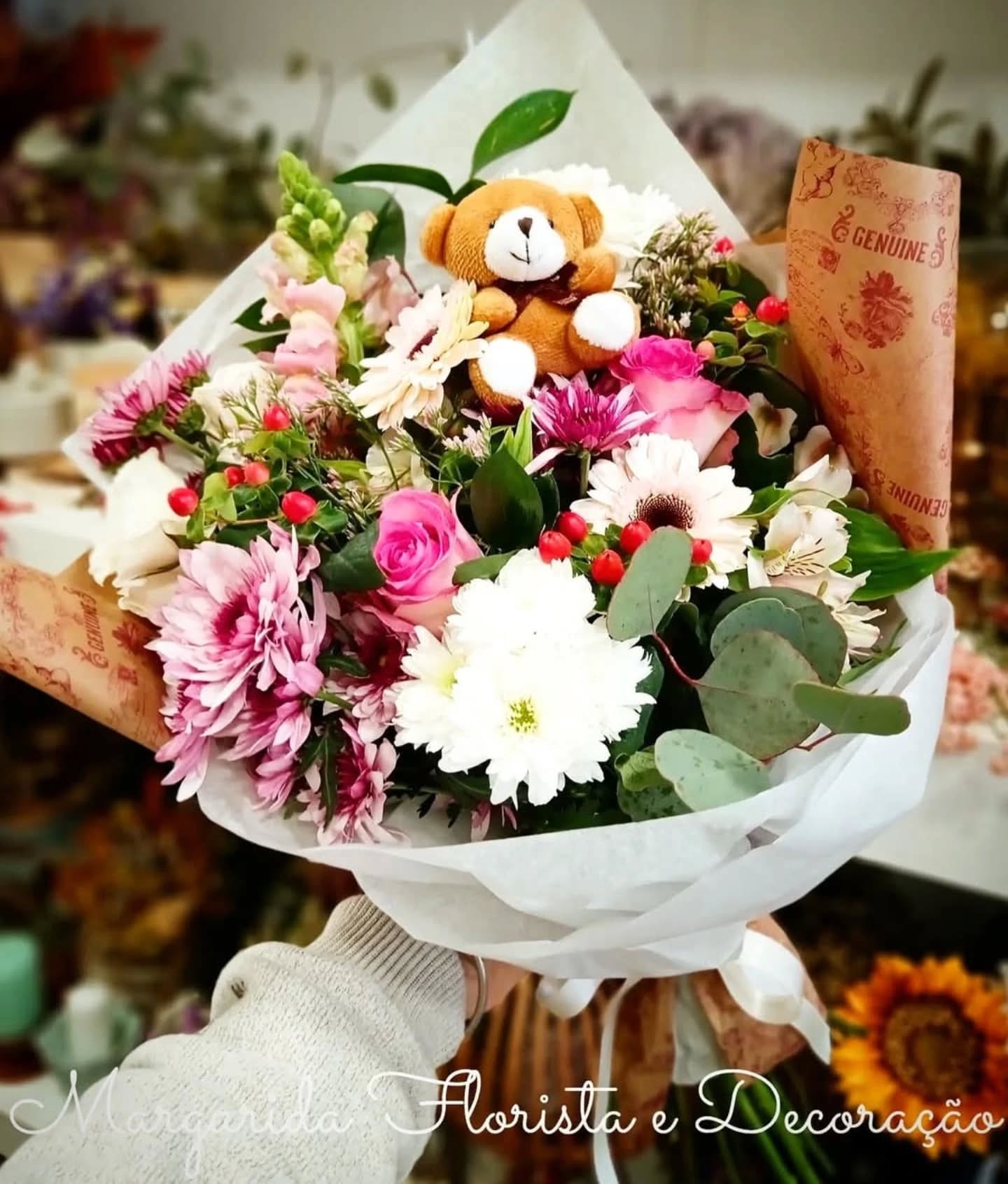Buquê de flores com ursinho de pelúcia e papel com texto GENUINE