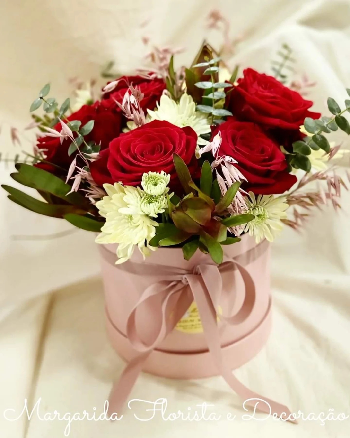 Arranjo floral com rosas vermelhas e flores brancas em caixa rosa com laço