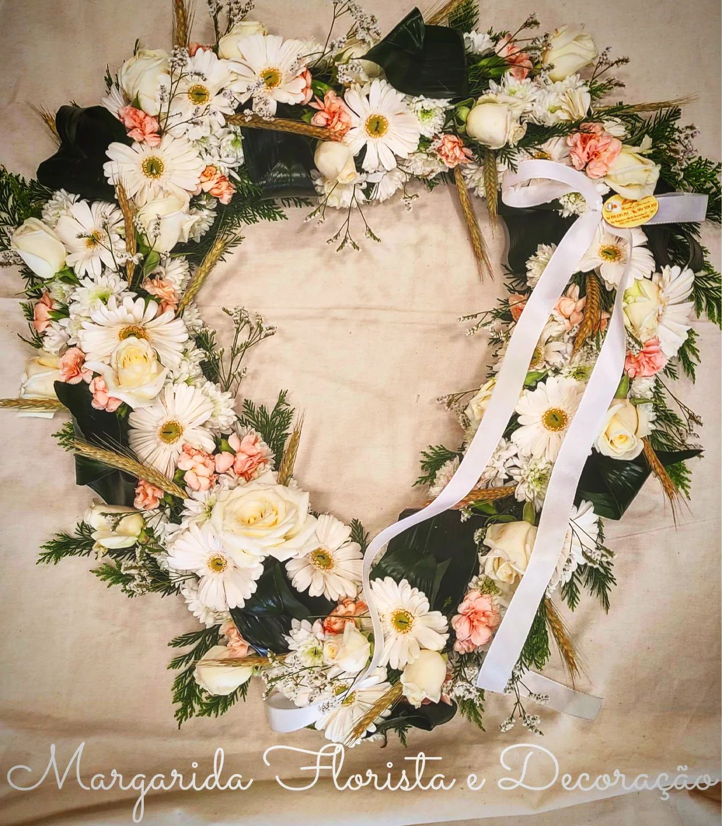 Coroa floral em forma de coração com flores brancas e cor-de-rosa e laço branco