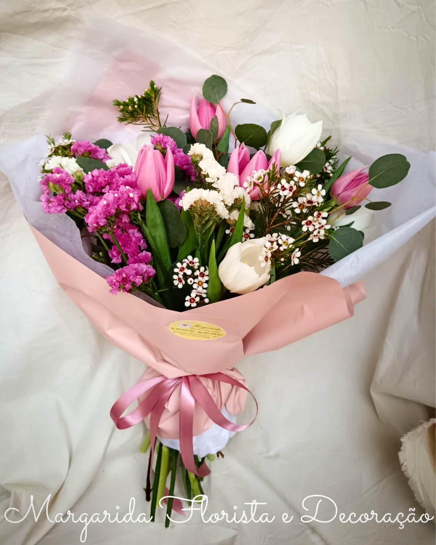 Buquê de flores com tulipas rosa e brancas e flores pequenas, embrulho rosa claro com fita