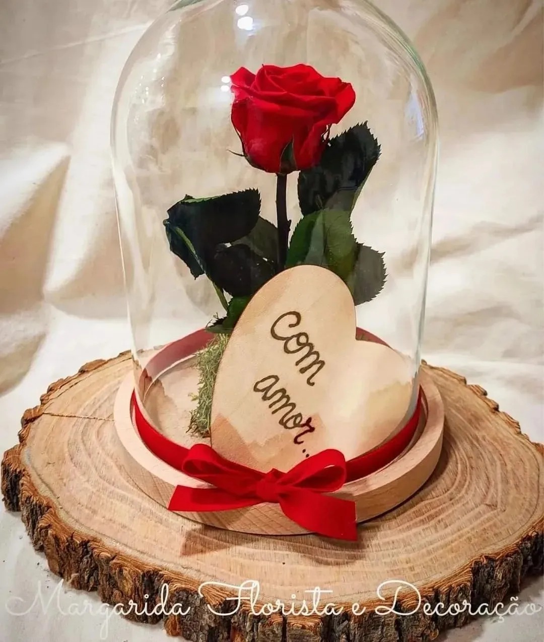 Rosa vermelha artificial sob cúpula de vidro em base de madeira com placa 'com amor' e fita vermelha