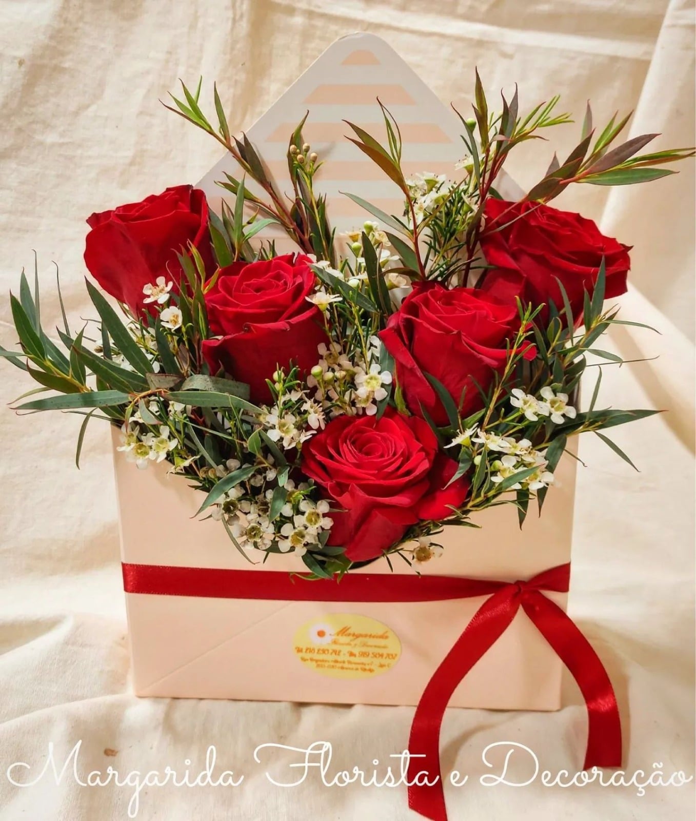 Arranjo floral em caixa envelope com rosas vermelhas e folhagem verde