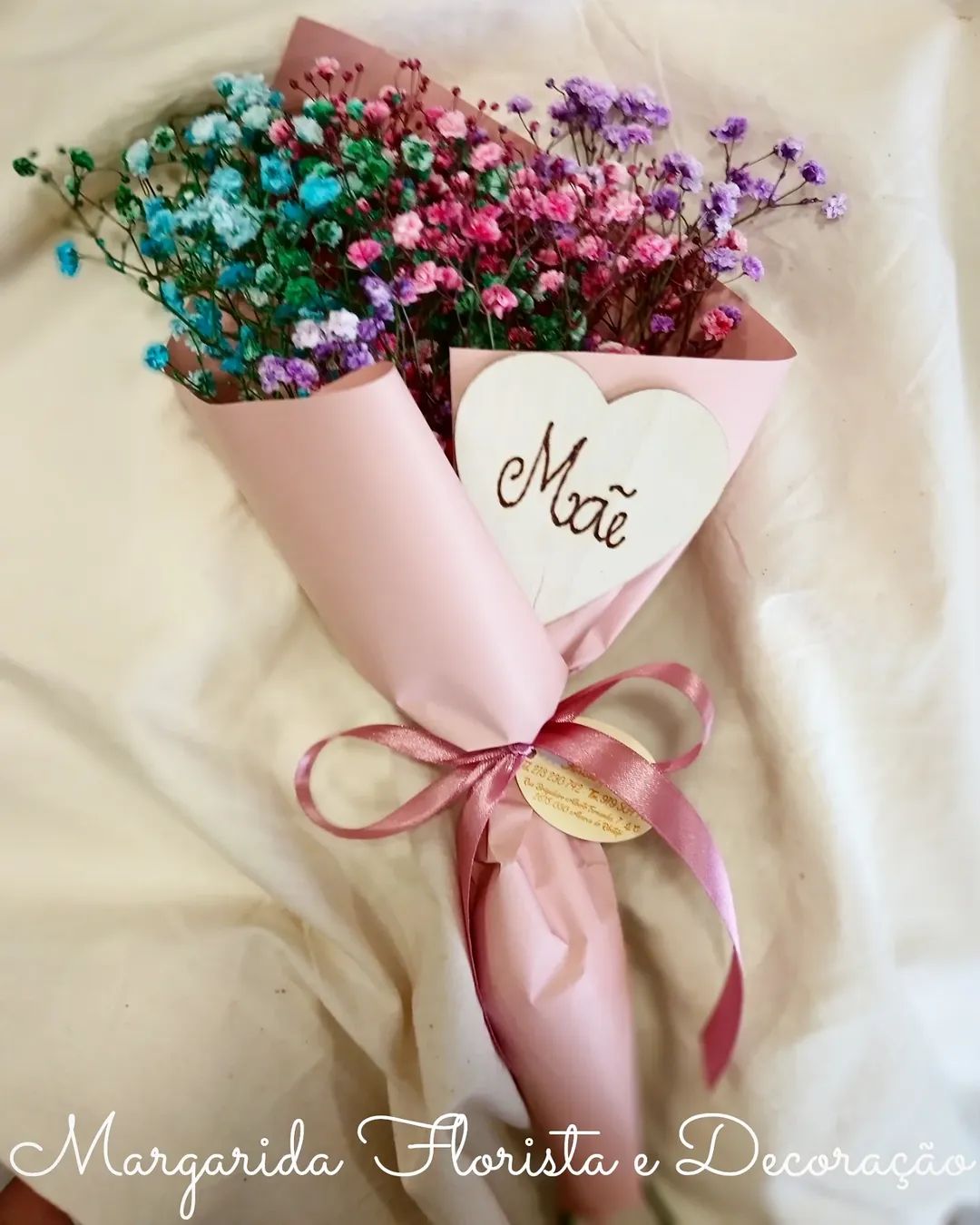 Bouquet de flores coloridas em papel cor de rosa com laço e coração de madeira