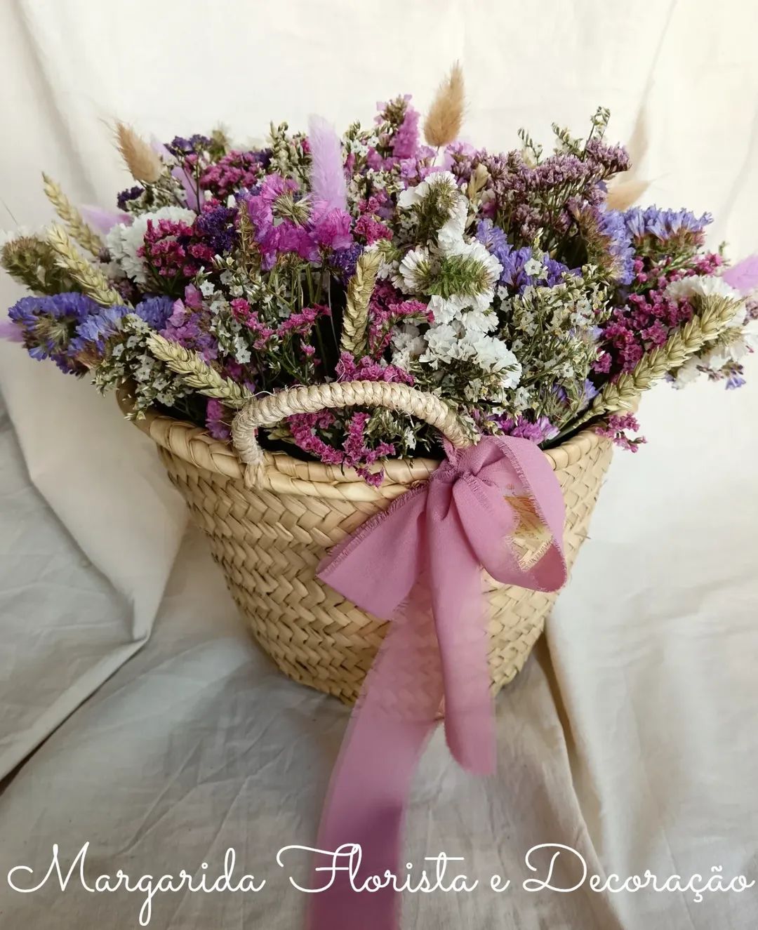 Cesto de vime com flores secas coloridas e laço rosa