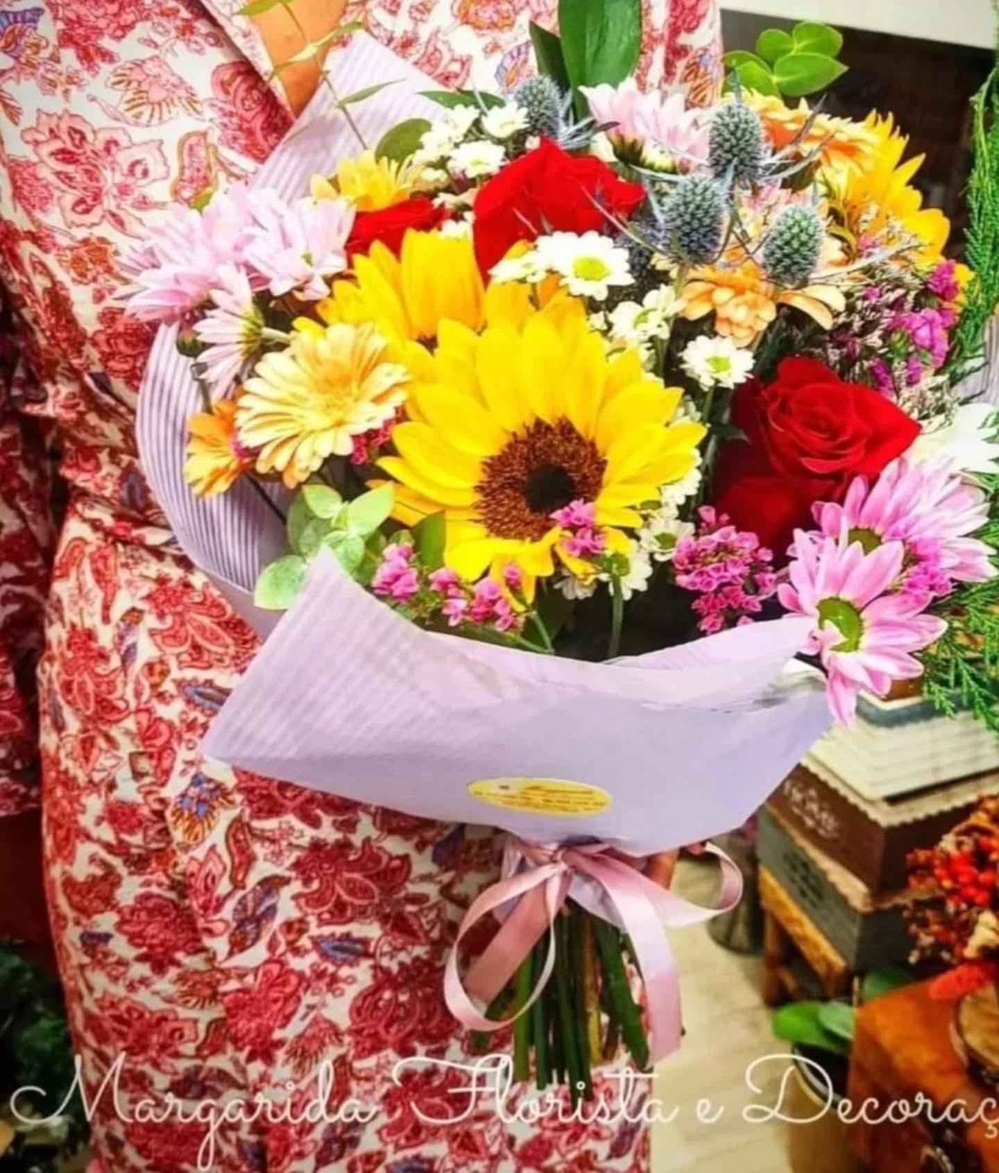 Buquê de flores coloridas embalado em papel lilás com fita cor de rosa