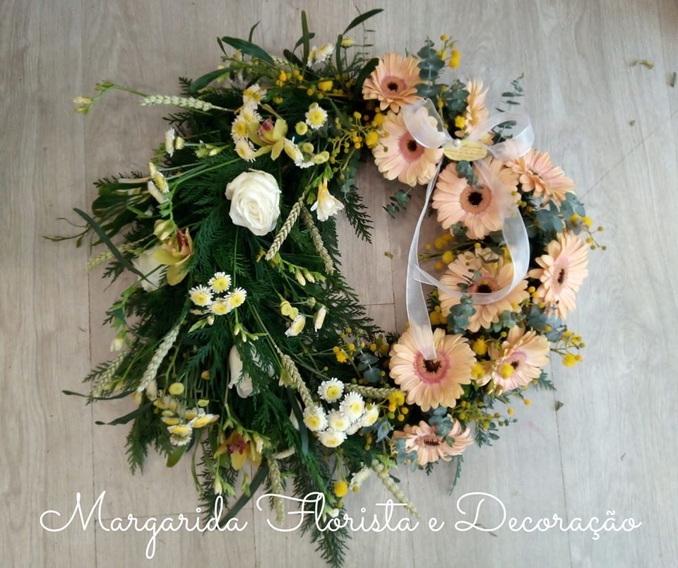 Coroa floral com flores brancas e cor-de-rosa sobre fundo de madeira clara