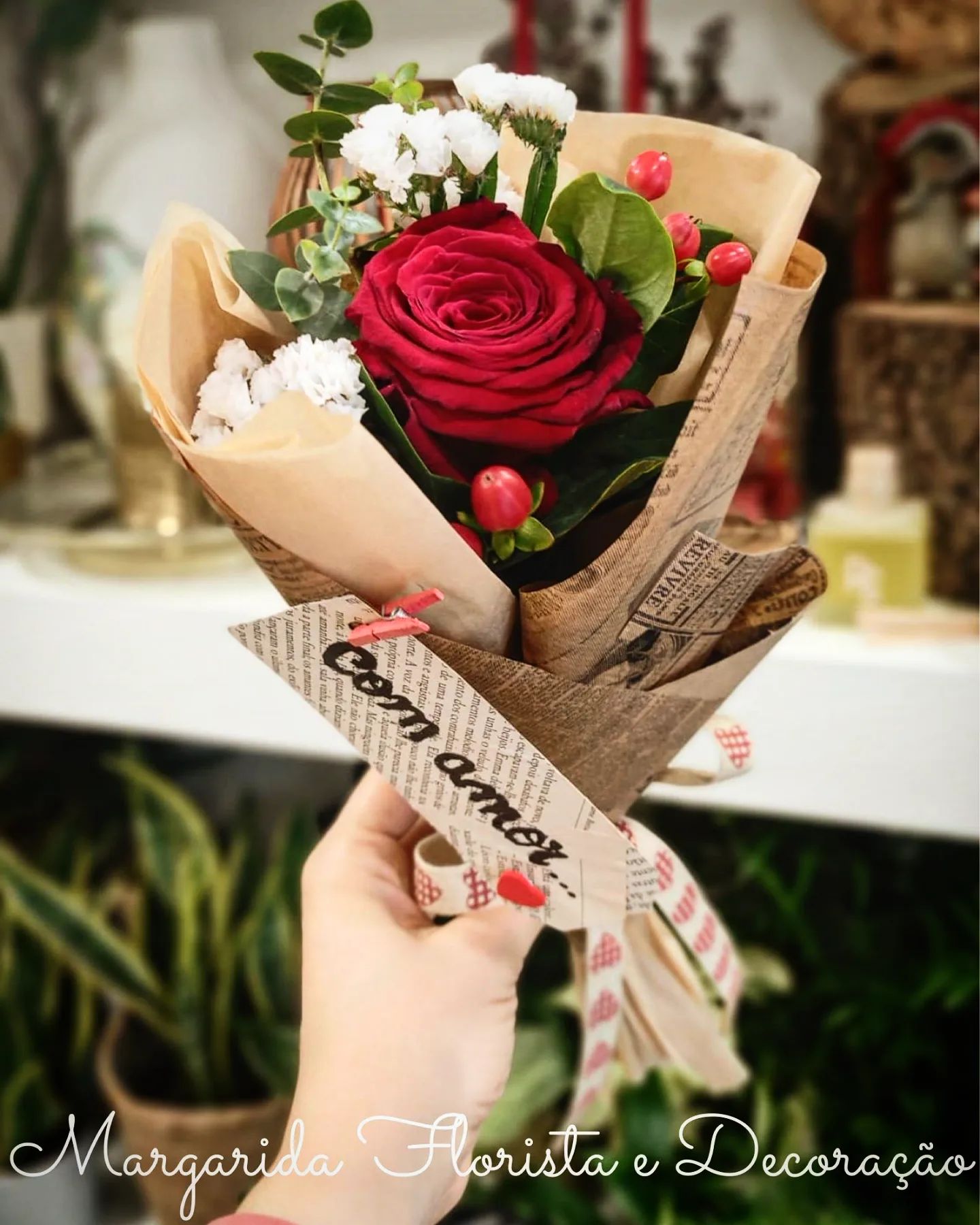 Buquê pequeno com rosa vermelha e flores brancas envolto em papel castanho decorativo