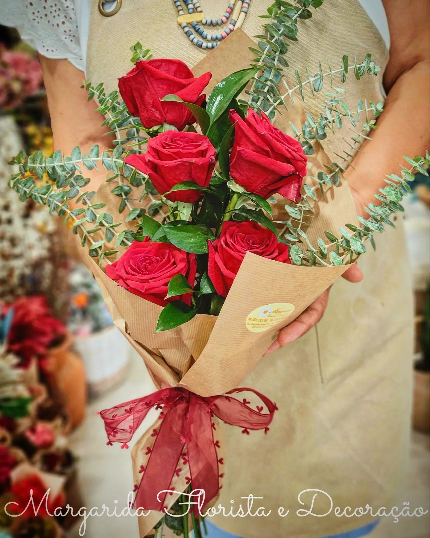 Bouquet de rosas vermelhas com eucalipto envolto em papel castanho com laço vermelho