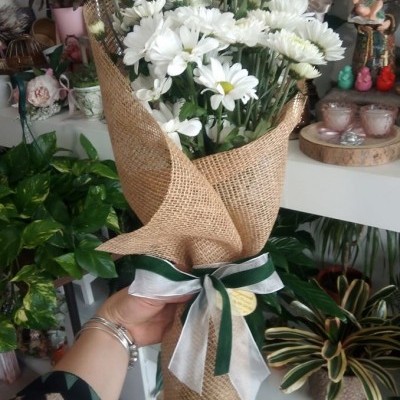 Bouquet de flores brancas envolto em juta com fita verde e branca