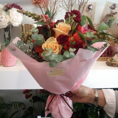 Ramo de flores em papel cor-de-rosa com rosas amarelas e flores vermelhas