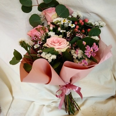 Bouquet de flores rosa e brancas com folhas verdes, embrulhado em papel rosa