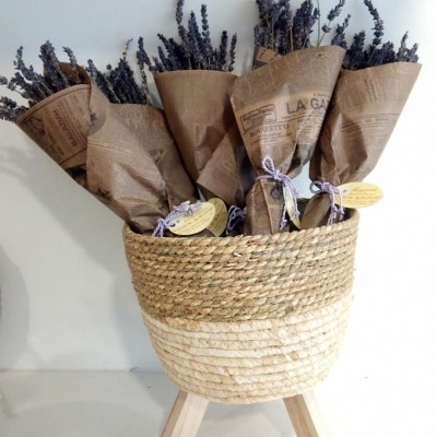 Vasos com flores secas de lavanda em papel castanho dentro de cesto de palha com base de madeira