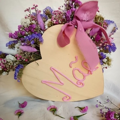 Arranjo floral seco em forma de coração com decoração em cordão rosa e fita rosa