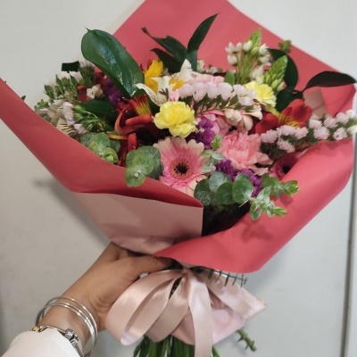 Ramo de flores coloridas embrulhado em papel rosa com fita cor-de-rosa