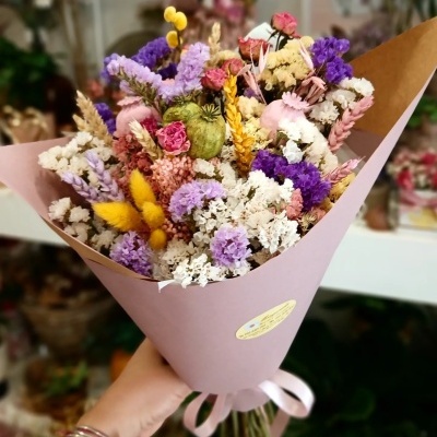 Bouquet colorido de flores secas em papel rosa com fita