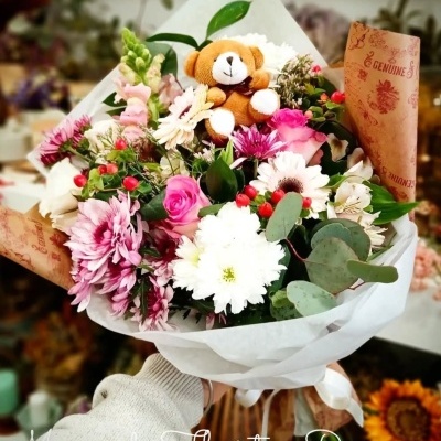 Buquê de flores com ursinho de pelúcia e papel com texto GENUINE