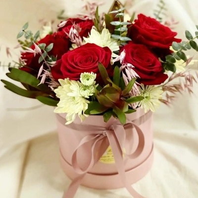 Arranjo floral com rosas vermelhas e flores brancas em caixa rosa com laço