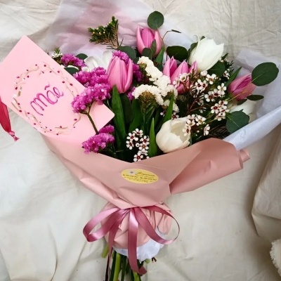 Buquê de flores com papel rosa e laço, cartão escrito Mãe