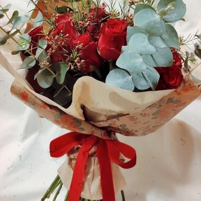 Buquê de flores rosas vermelhas e eucalipto em papel floral com fita vermelha