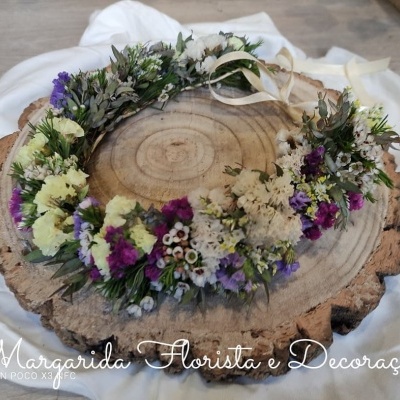Coroa de flores naturais e secas coloridas sobre tronco de madeira rústica