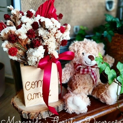 Arranjo de flores secas em vaso de madeira com ursinho de pelúcia ao lado