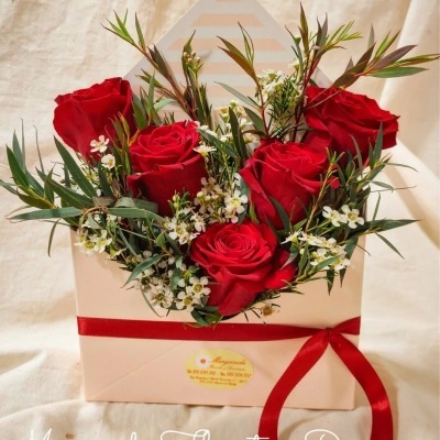 Arranjo floral em caixa envelope com rosas vermelhas e folhagem verde