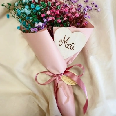 Bouquet de flores coloridas em papel cor de rosa com laço e coração de madeira