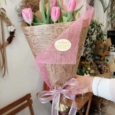 Bouquet de tulipas cor-de-rosa envoltas em papel com texto e laço rosa