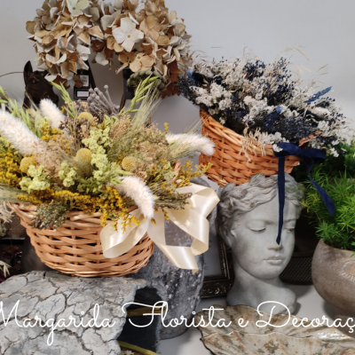 Três arranjos florais decorativos com flores secas e plantas artificiais em cestos e vasos