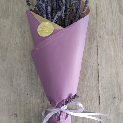 Buquê de lavanda embalado em papel roxo e bege, amarrado com fita branca