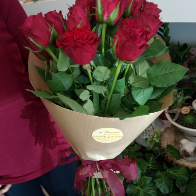Bouquet de rosas vermelhas envolvido em papel kraft com laço vermelho numa florista