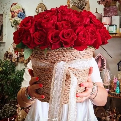 Cesto trançado com fita de renda e rosas vermelhas, decorado, segurado por pessoa.