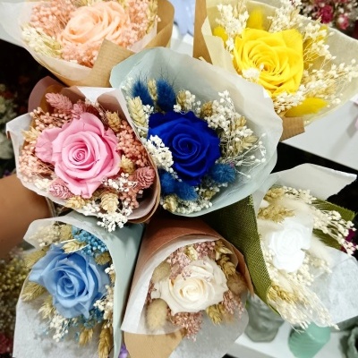 Buquês de flores preservadas em várias cores envoltos em papel colorido