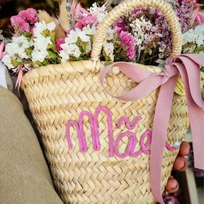 Cesto de palha com laço rosa e flores secas coloridas