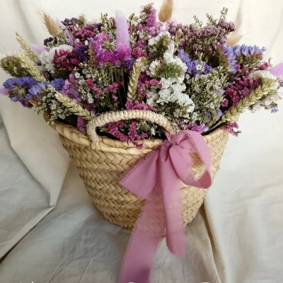 Cesto de vime com flores secas coloridas e laço rosa