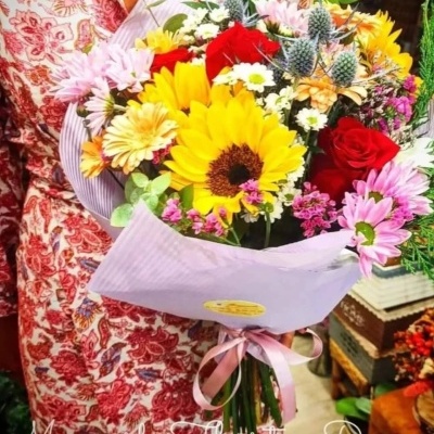 Buquê de flores coloridas embalado em papel lilás com fita cor de rosa