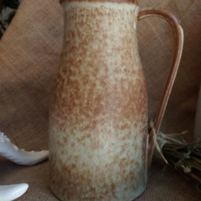 Jarro de cerâmica castanho e bege com textura irregular sobre juta