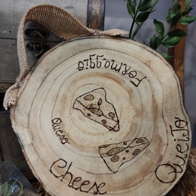 Disco de madeira decorativo com desenhos de queijo e palavras em várias línguas