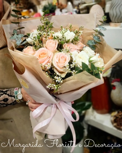 Bouquet de rosas cor-de-rosa claras e flores brancas com folhagem verde, embrulhado em papel bege com fita cor-de-rosa