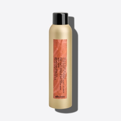 Frasco metálico dourado com tampa preta e etiqueta rosa de shampoo seco Davines