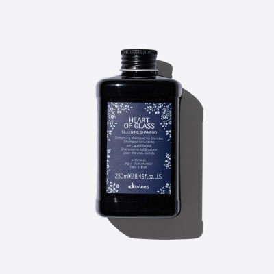 Frasco preto de shampoo Heart of Glass da marca Davines com rótulo azul decorado com flores brancas