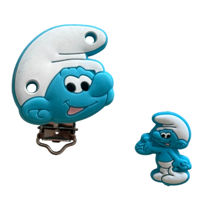 Dois acessórios com imagem dos Smurfs em azul e branco, chupeta com clip metálico e pequena figura em relevo.