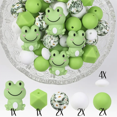 Contas para bijuteria com rãs verdes, bolas brancas, verdes e florais num prato de vidro