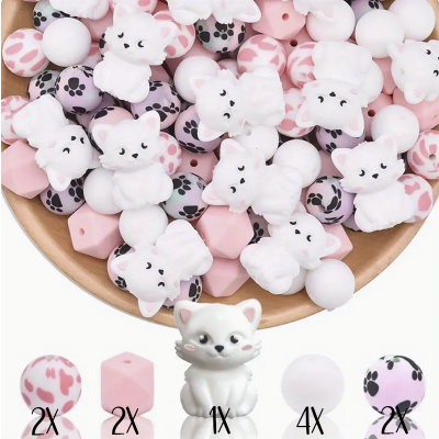 Contas de silicone rosa, branco e lilás com formas variadas e desenhos de gatos num prato de madeira.