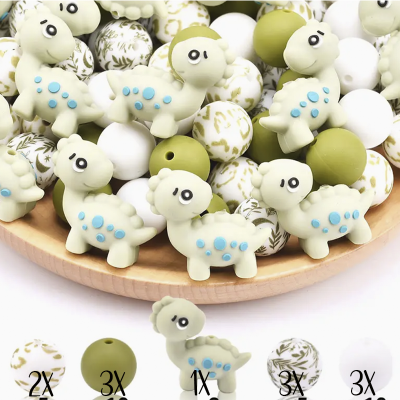 Contas redondas e em forma de dinossauro coloridas num prato de madeira